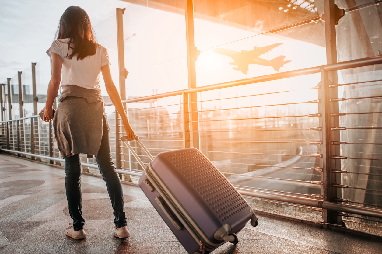 Young woman pulling suitcase in airport terminal.