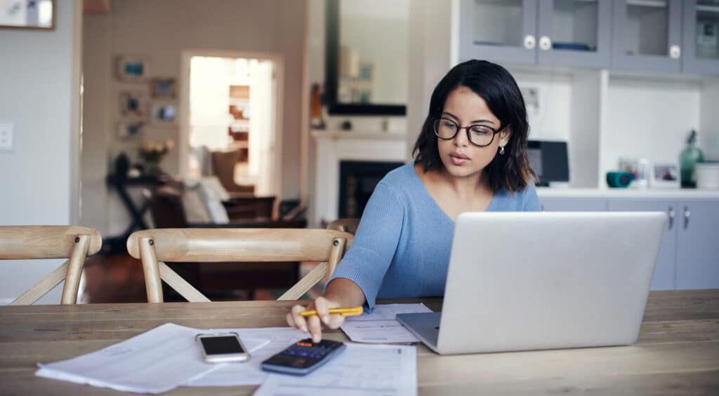 Woman sitting at laptop calculating leftover budget.