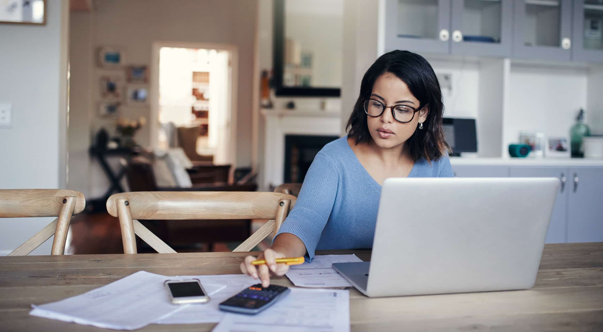 Woman sitting at laptop calculating leftover budget.