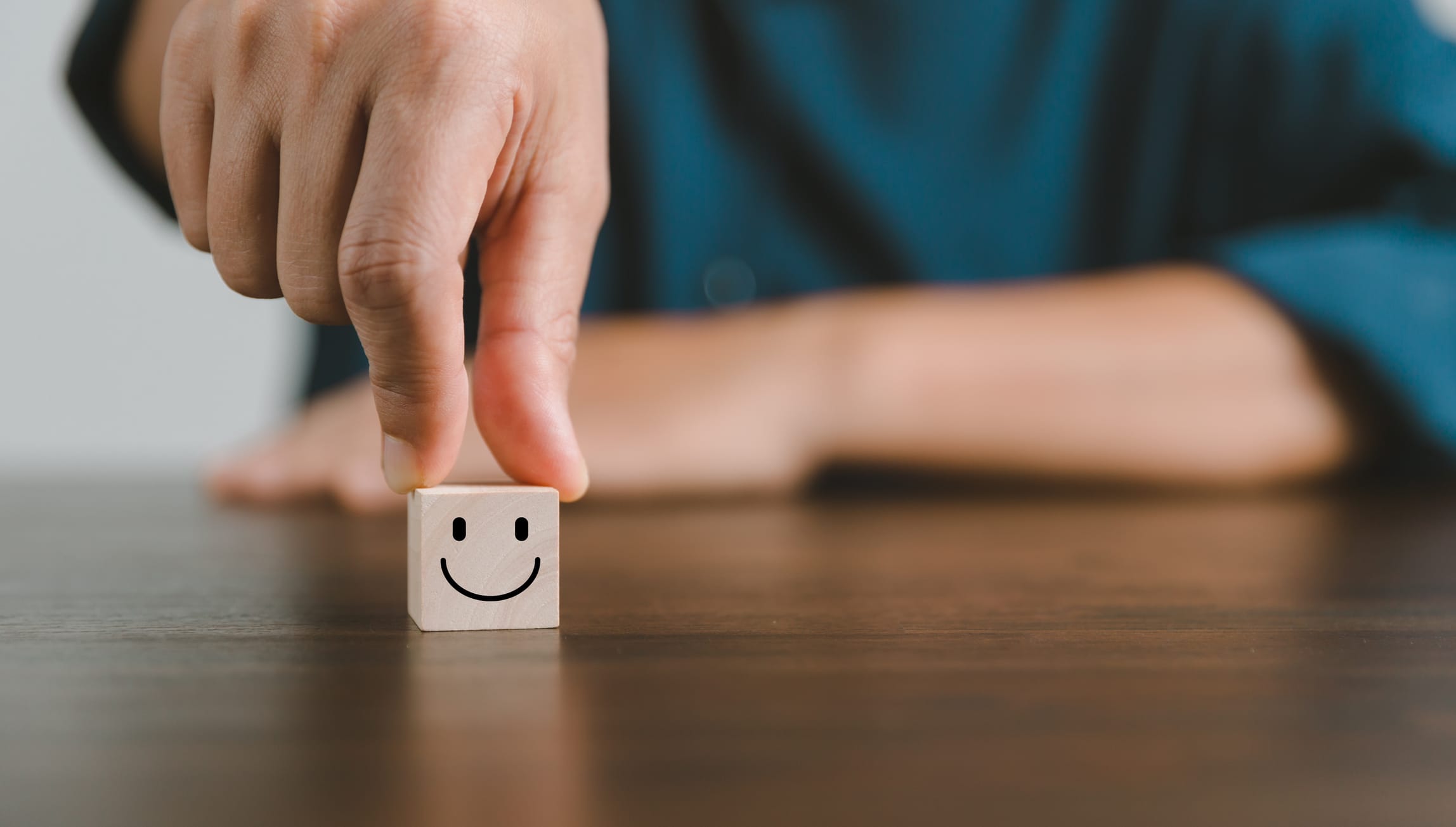 Image shows a small wooden cube with a smiley face drawn on it, representing a happy customer.