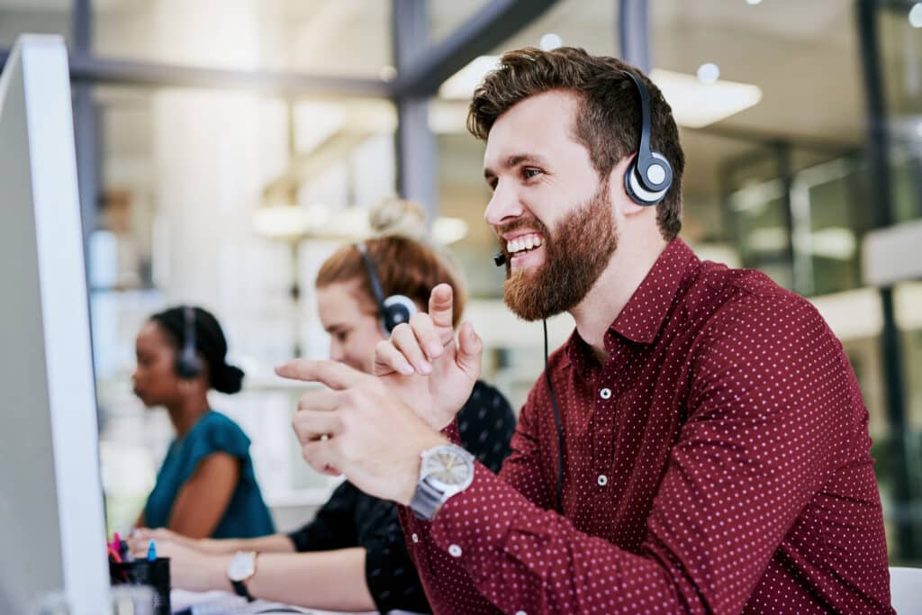 Smiling man answers a customer's call in a contact centre.