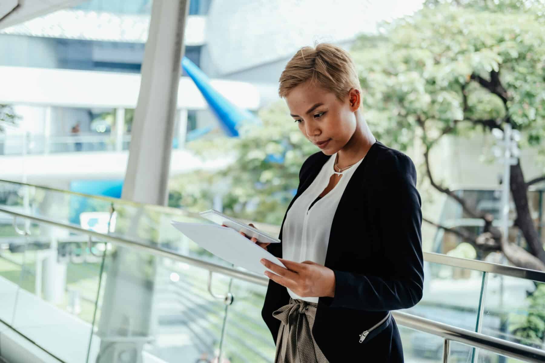 Woman reading a document while standing on a terrace.