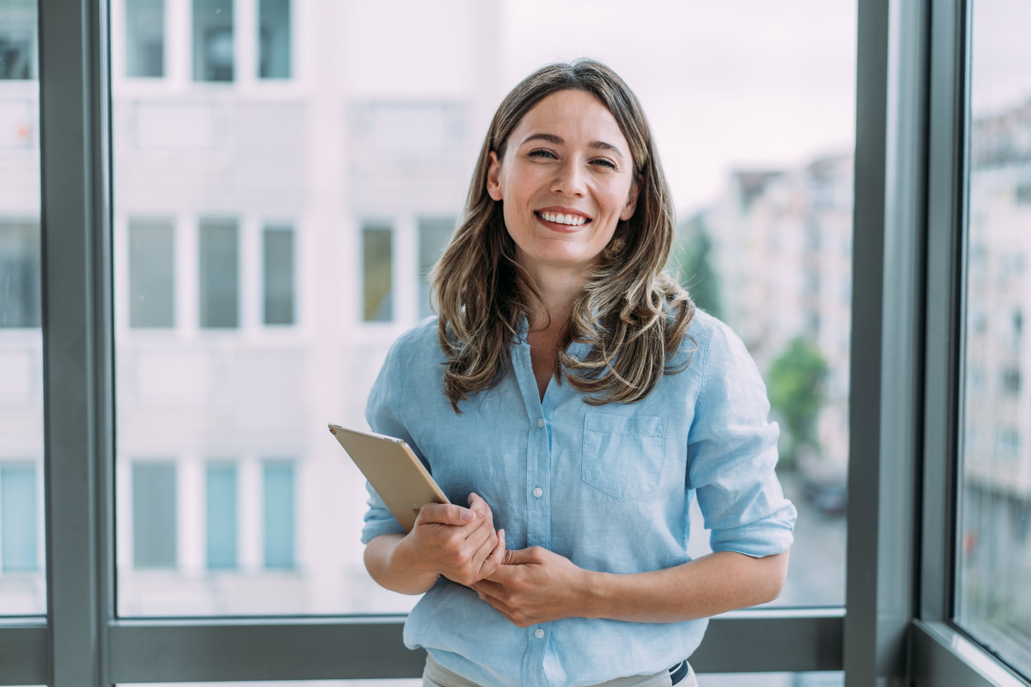 Young professional woman standing in the office and holding a tablet.