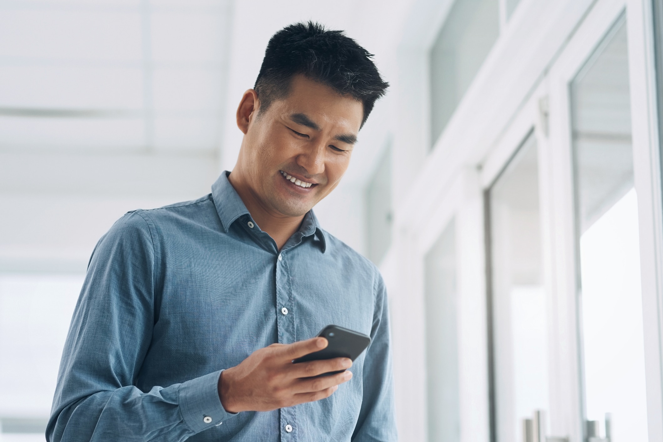 Happy businessman using a phone and social media at the office.