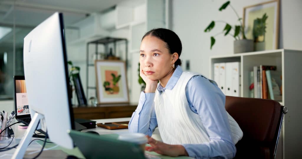 Woman looking thoughtfully at a computer screen. Crafting winning tenders and proposals