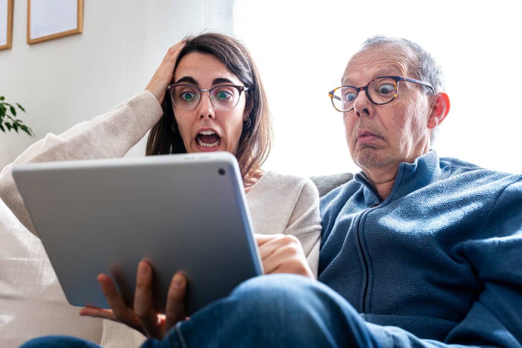 Two people reading a tablet and expressing surprise and disbelief