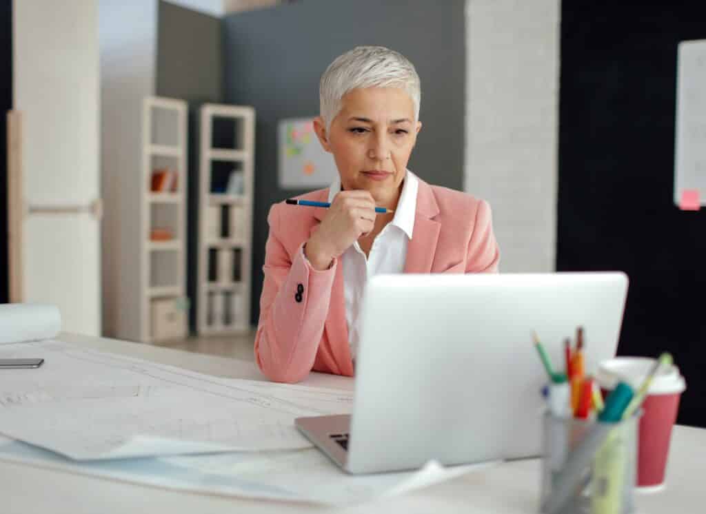 Woman in pink suit sitting at laptop editing